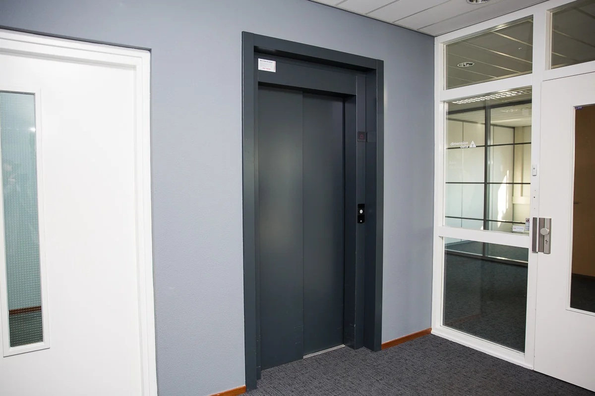 Grijze liftdeur in een modern kantoorpand aan de Laan van s-Gravenmade.